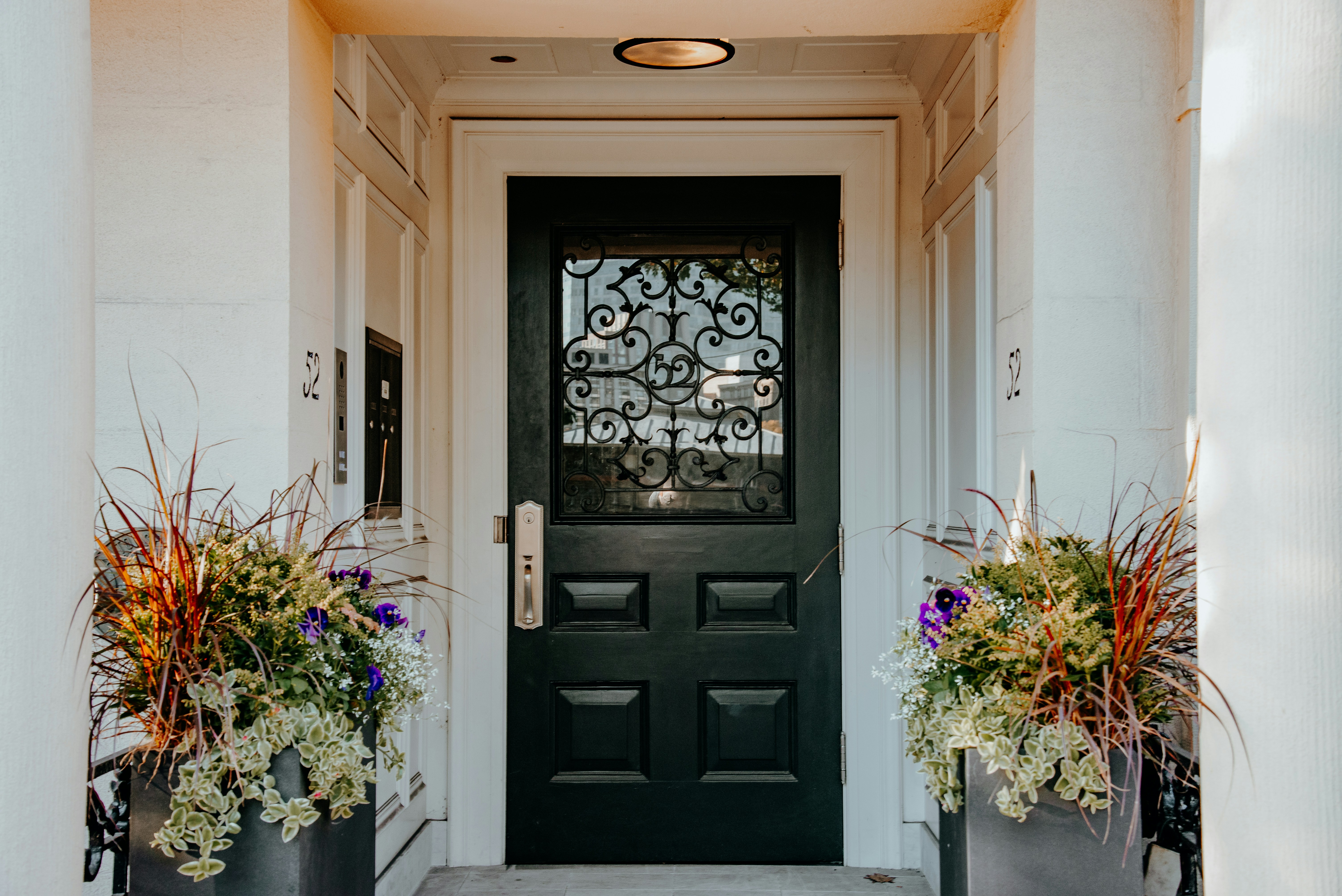 A black front door with two planters on either side of it