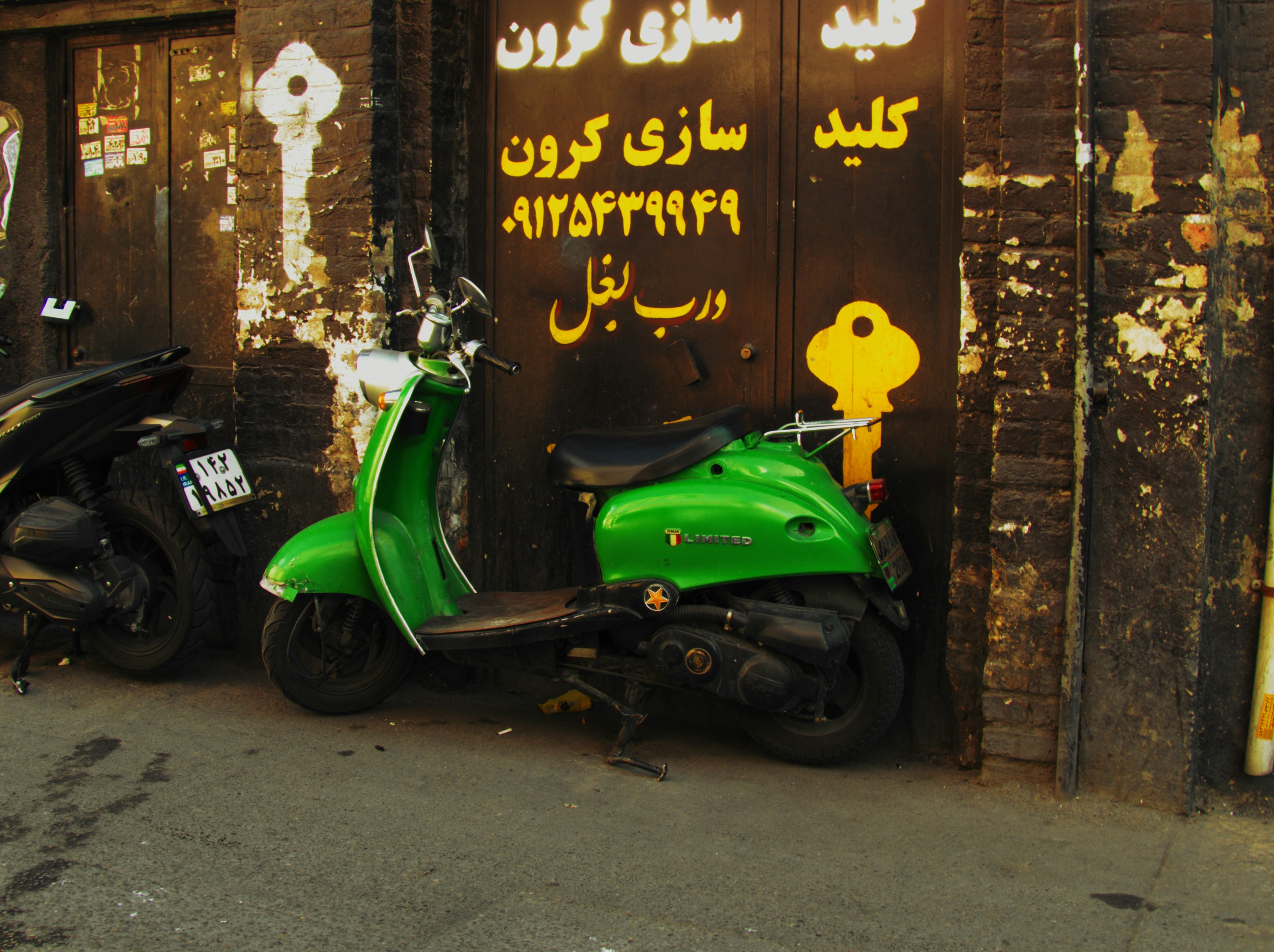 Uma scooter verde estacionada ao lado de um prédio de tijolos