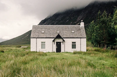 A white house in a field with a mountain in the background