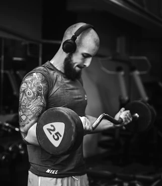A man in a gym holding a pair of dumbbells