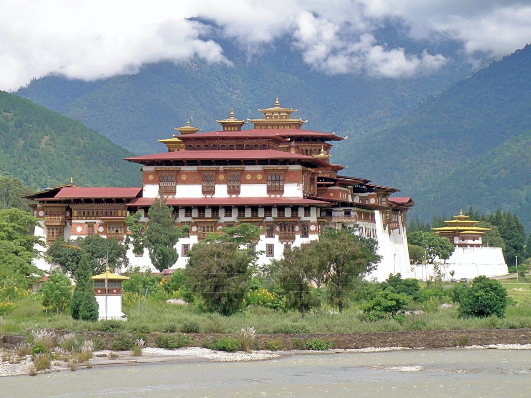 A large white and brown building sitting on top of a lush green hillside,