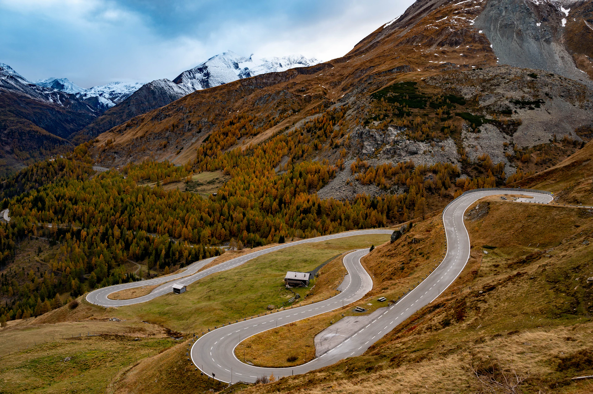 A winding road in the mountains with snow capped mountains in the background