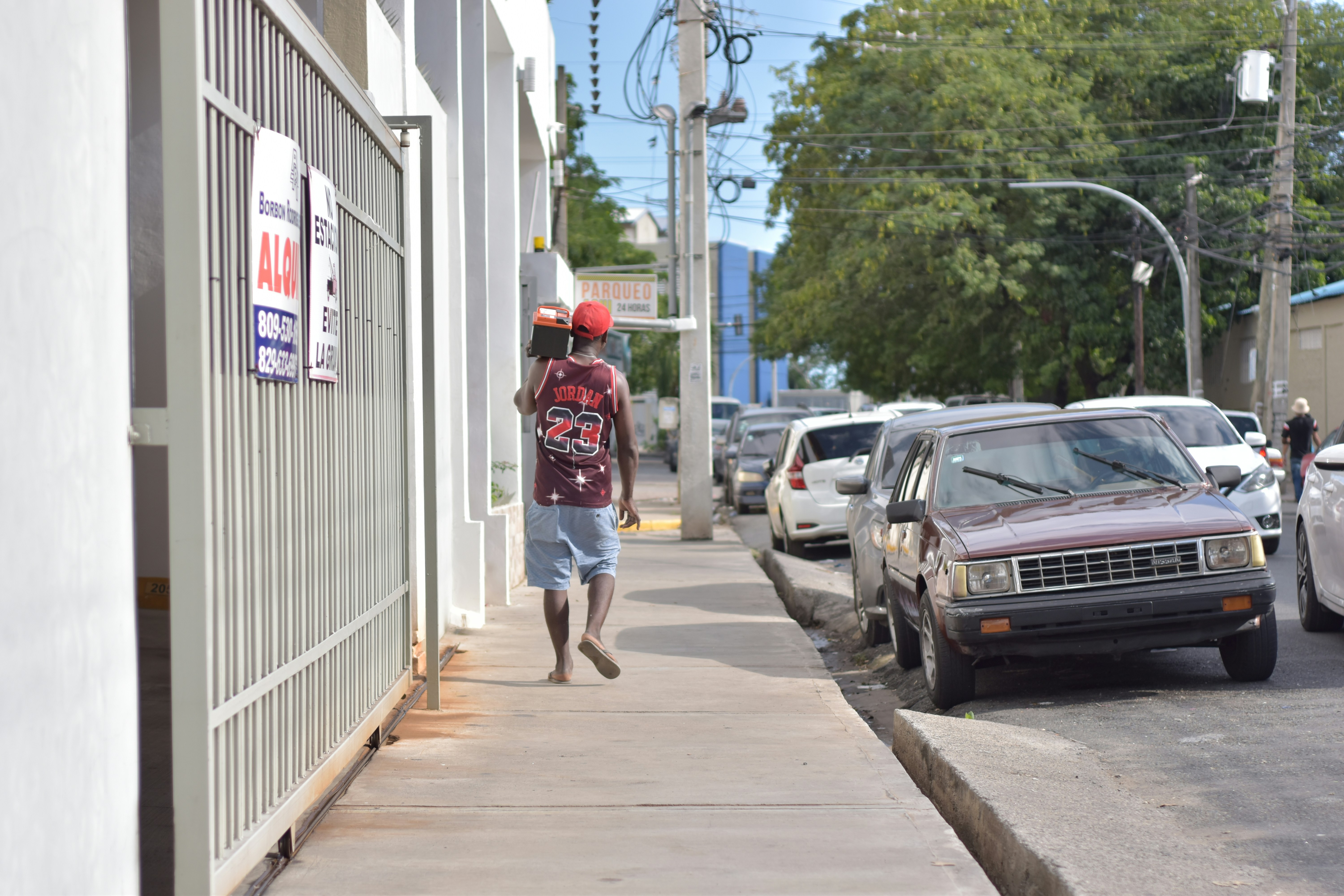 A man walking down a sidewalk next to parked cars