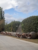 A long row of cement pots sitting on the side of a road