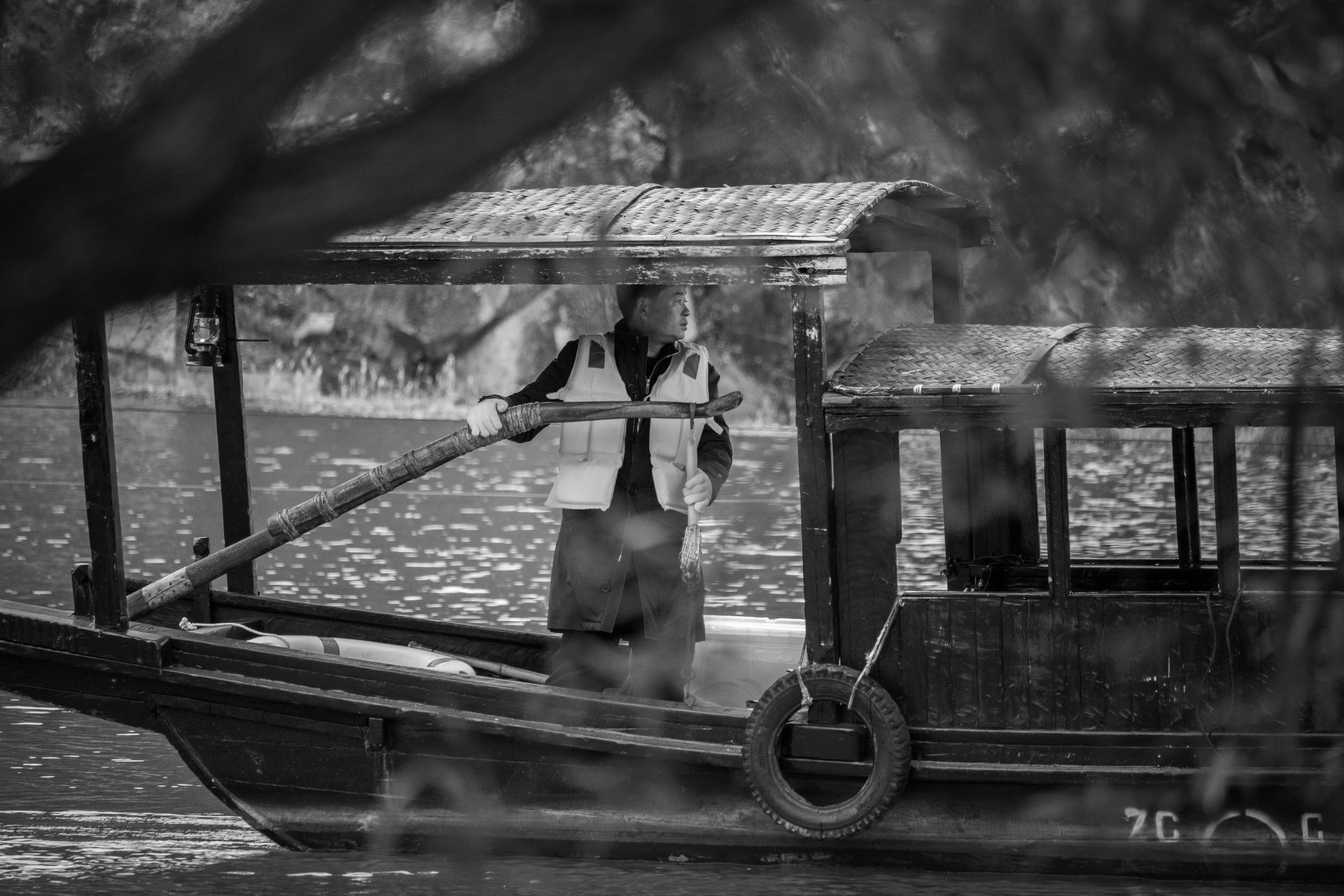 A black and white photo of a man standing on a boat