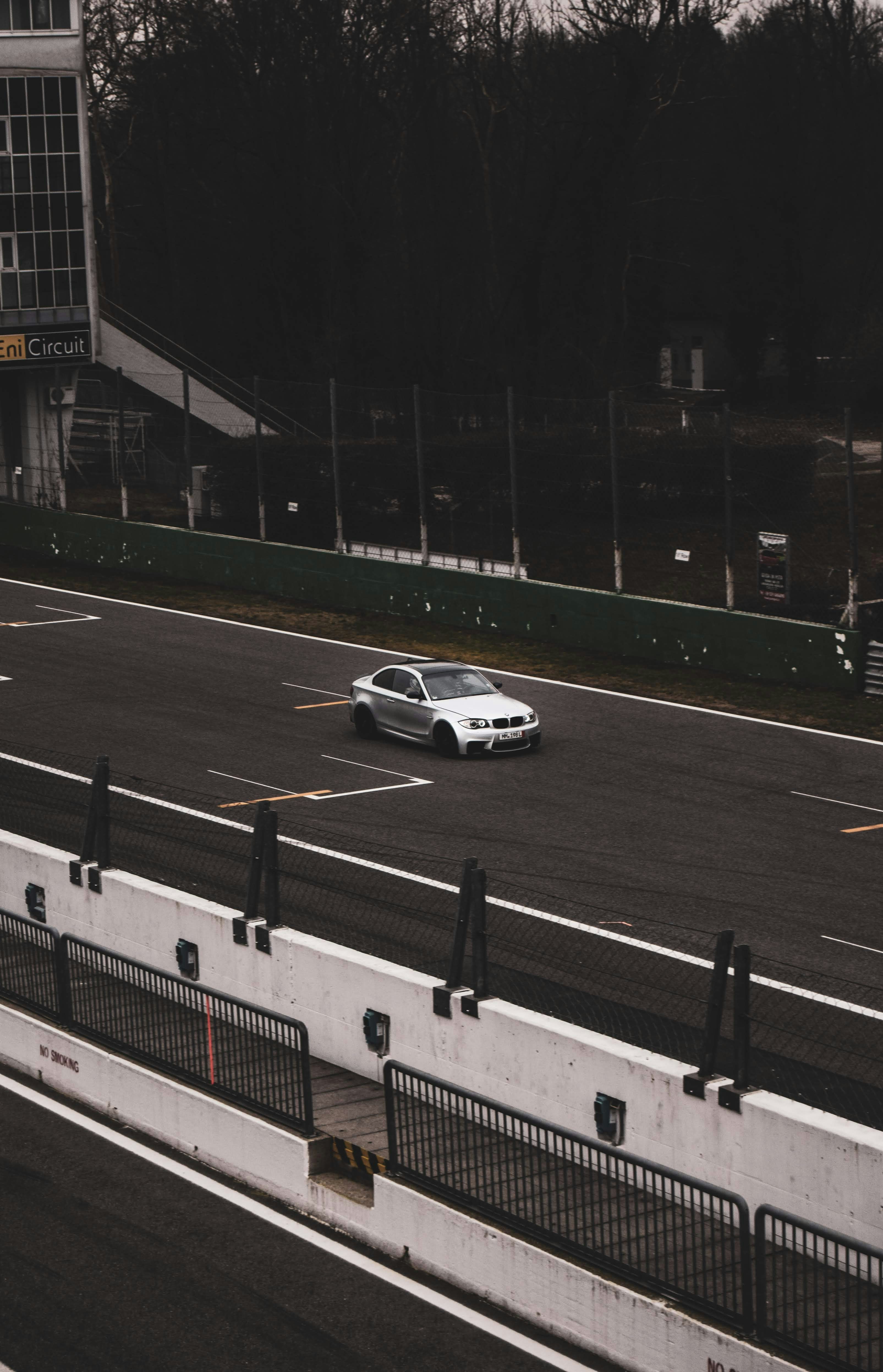 A white car driving down a highway next to a tall building