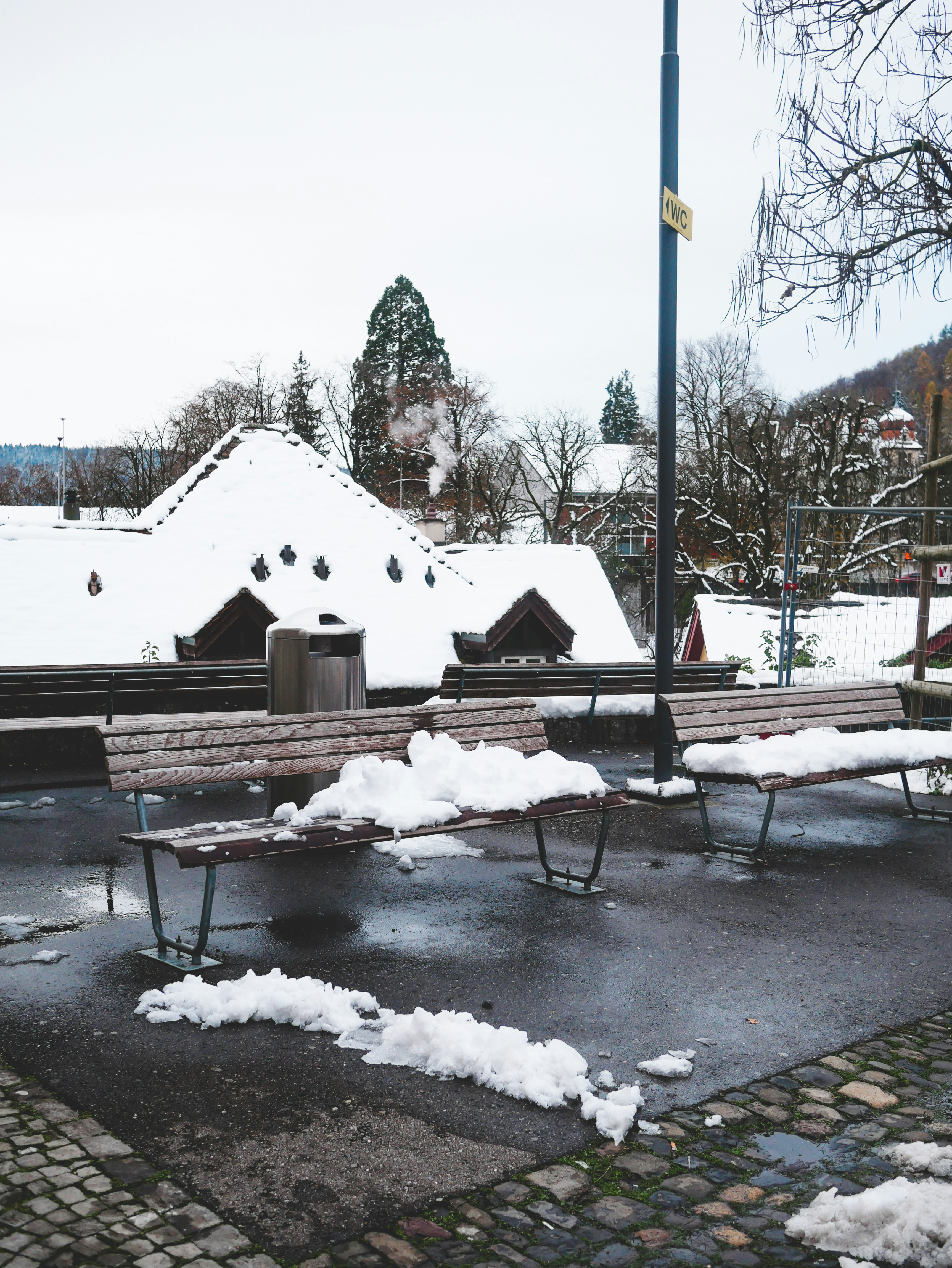 A park bench covered in snow next to a building