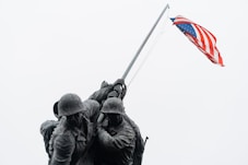 A couple of soldiers holding a flag on top of a hill