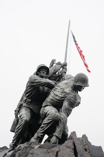 A statue of soldiers holding a flag on top of a hill