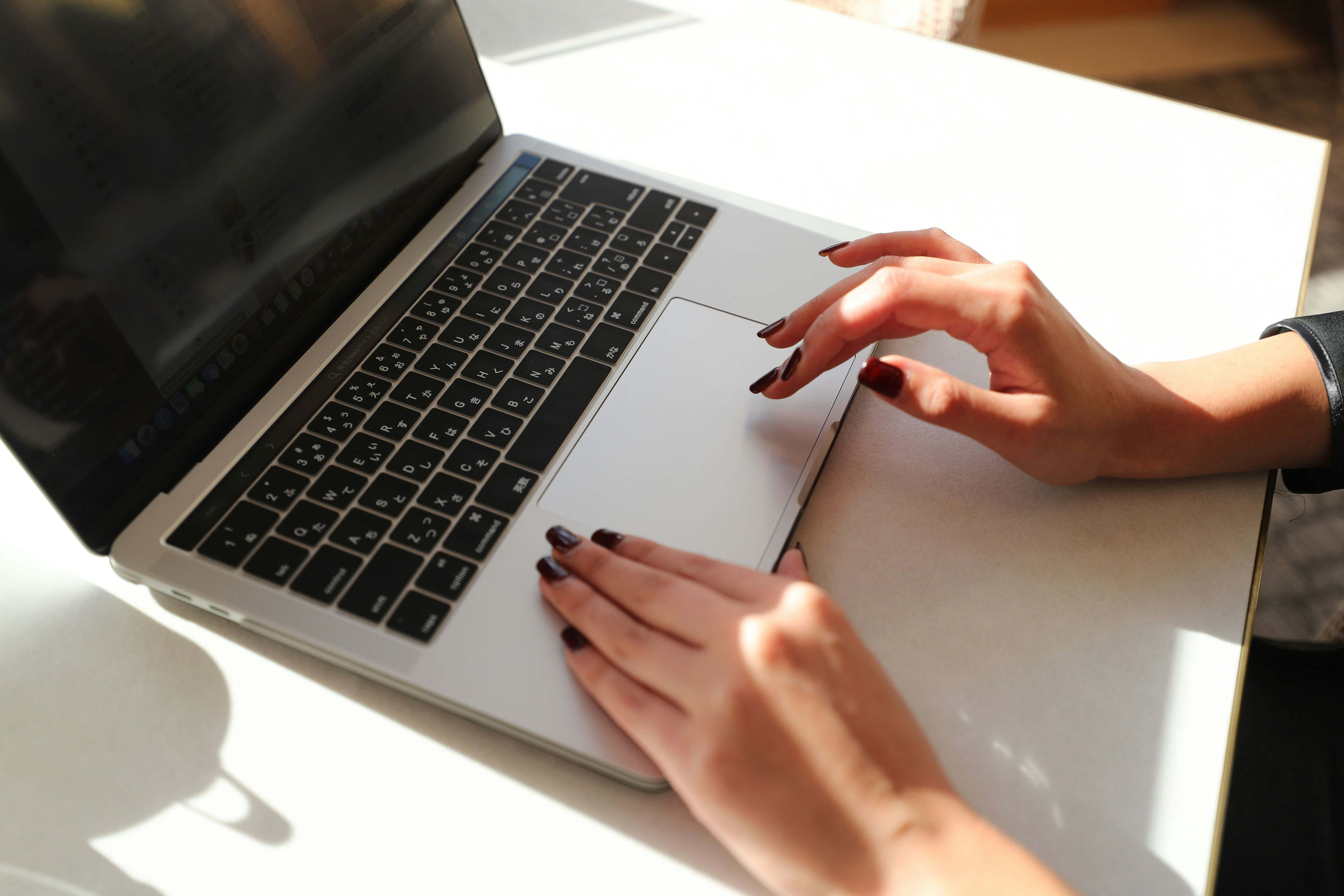 A woman sitting at a table using a laptop computer photo – Free Laptop ...
