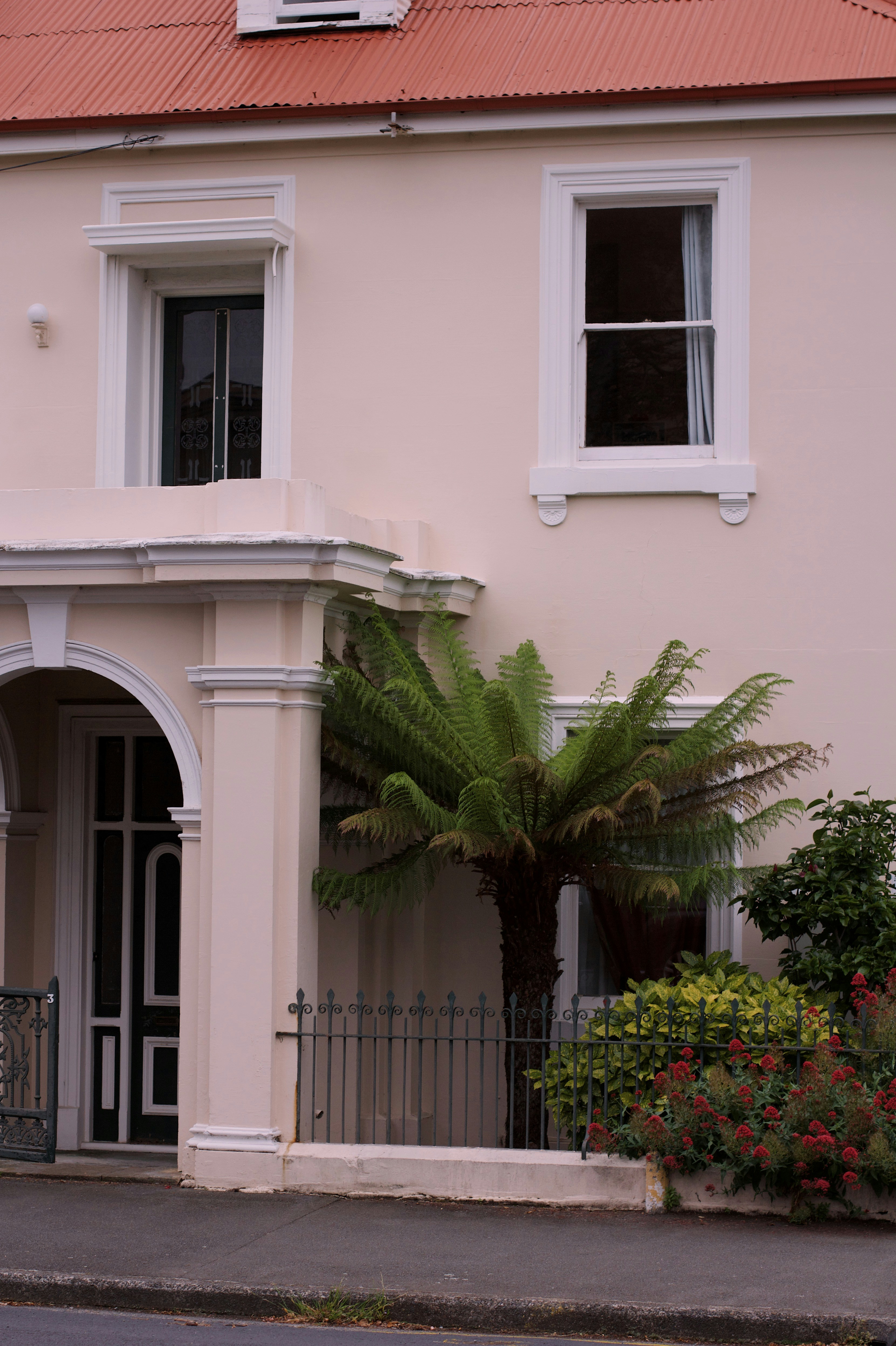 Una casa bianca con il tetto rosso e un'auto rossa parcheggiata davanti