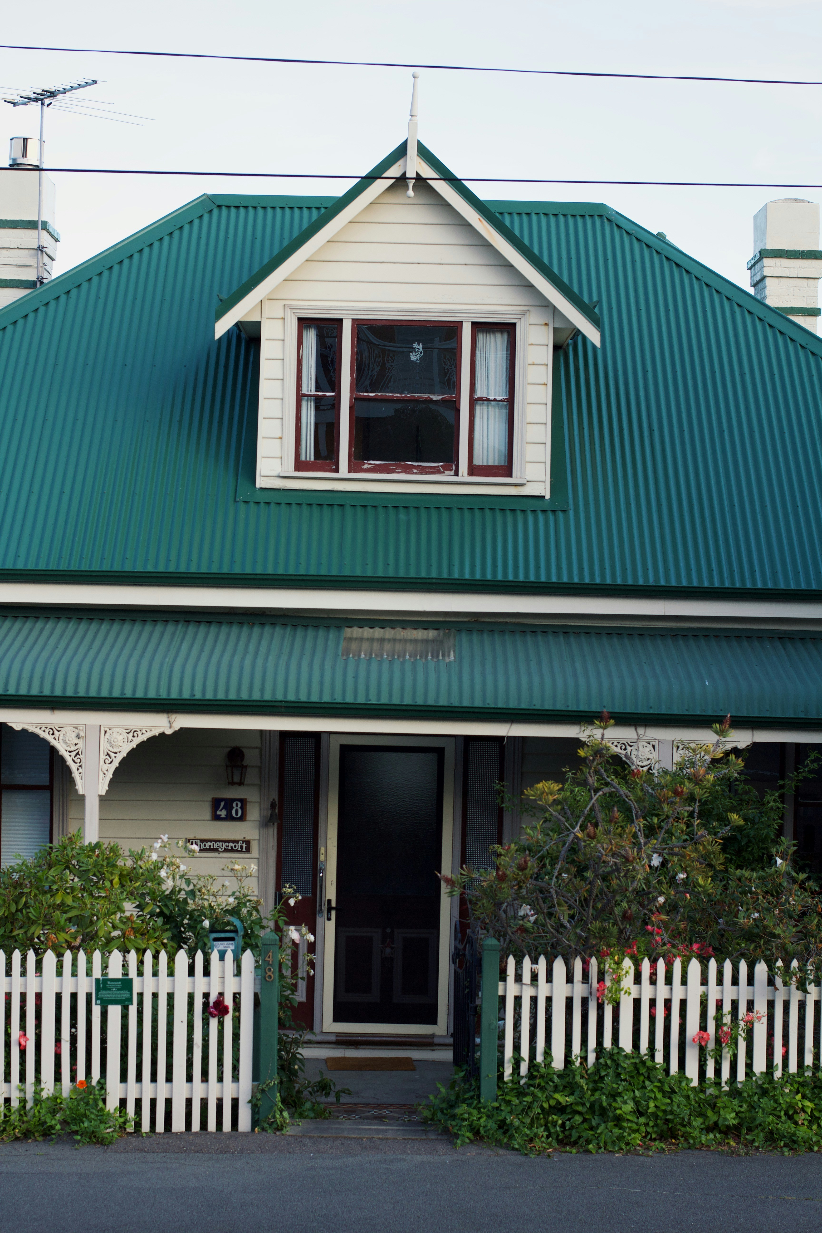 Una casa bianca con un tetto verde e una staccionata bianca