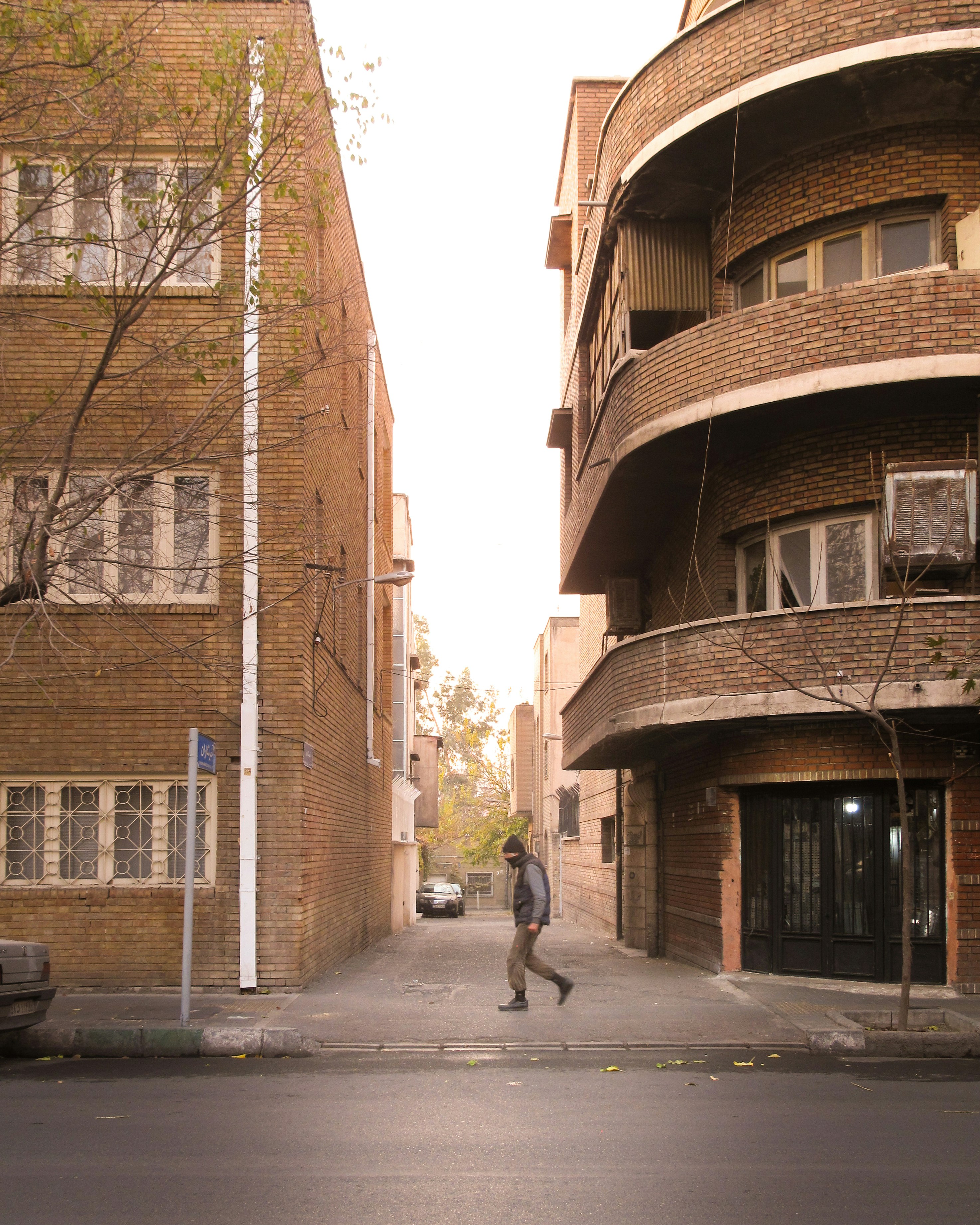 A man walking down a street next to tall buildings