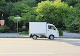 A white delivery truck driving down a street