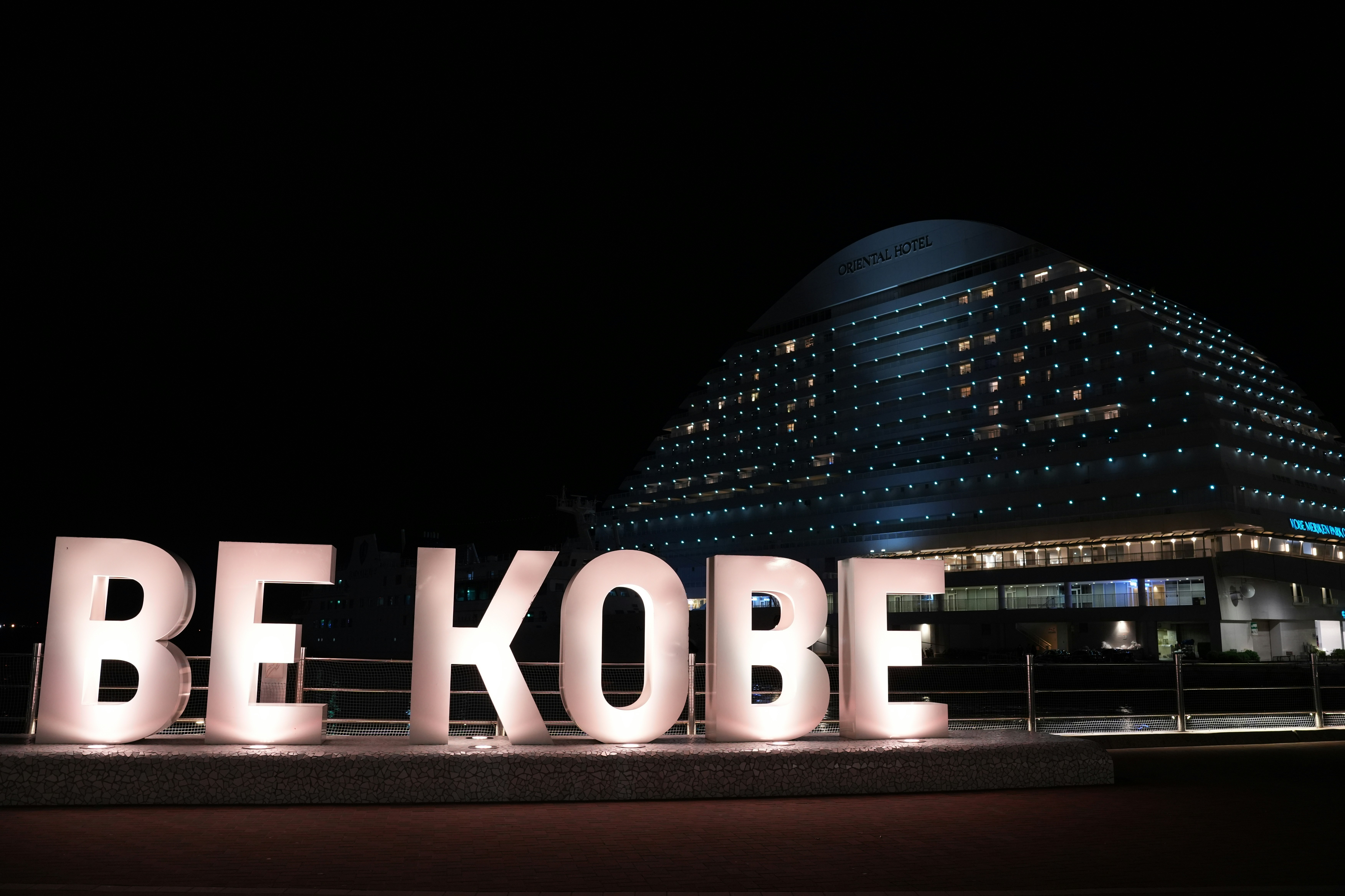 A large sign that says be kobe in front of a building