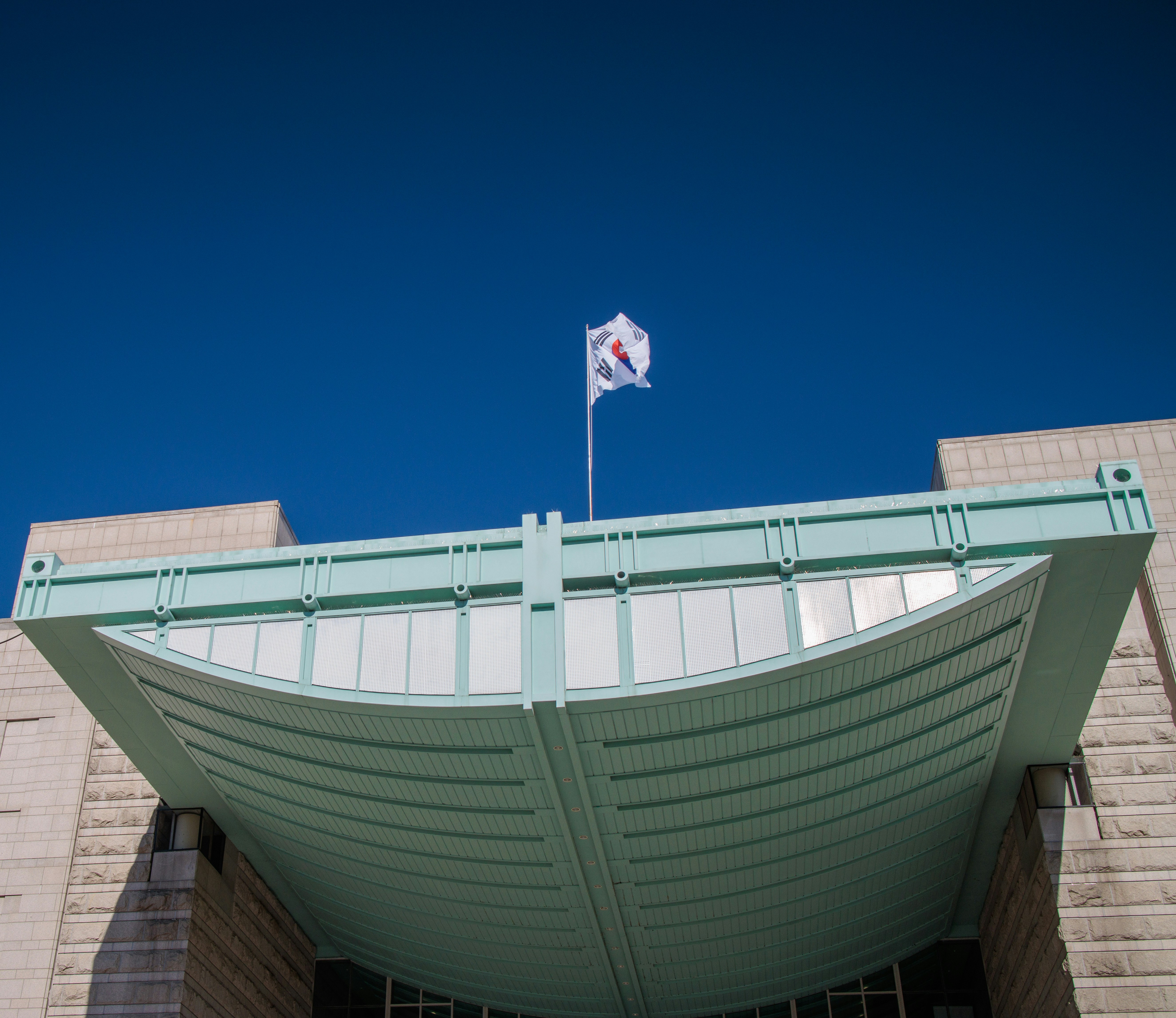 Modern school entrance showcasing a prominent architectural flagpole