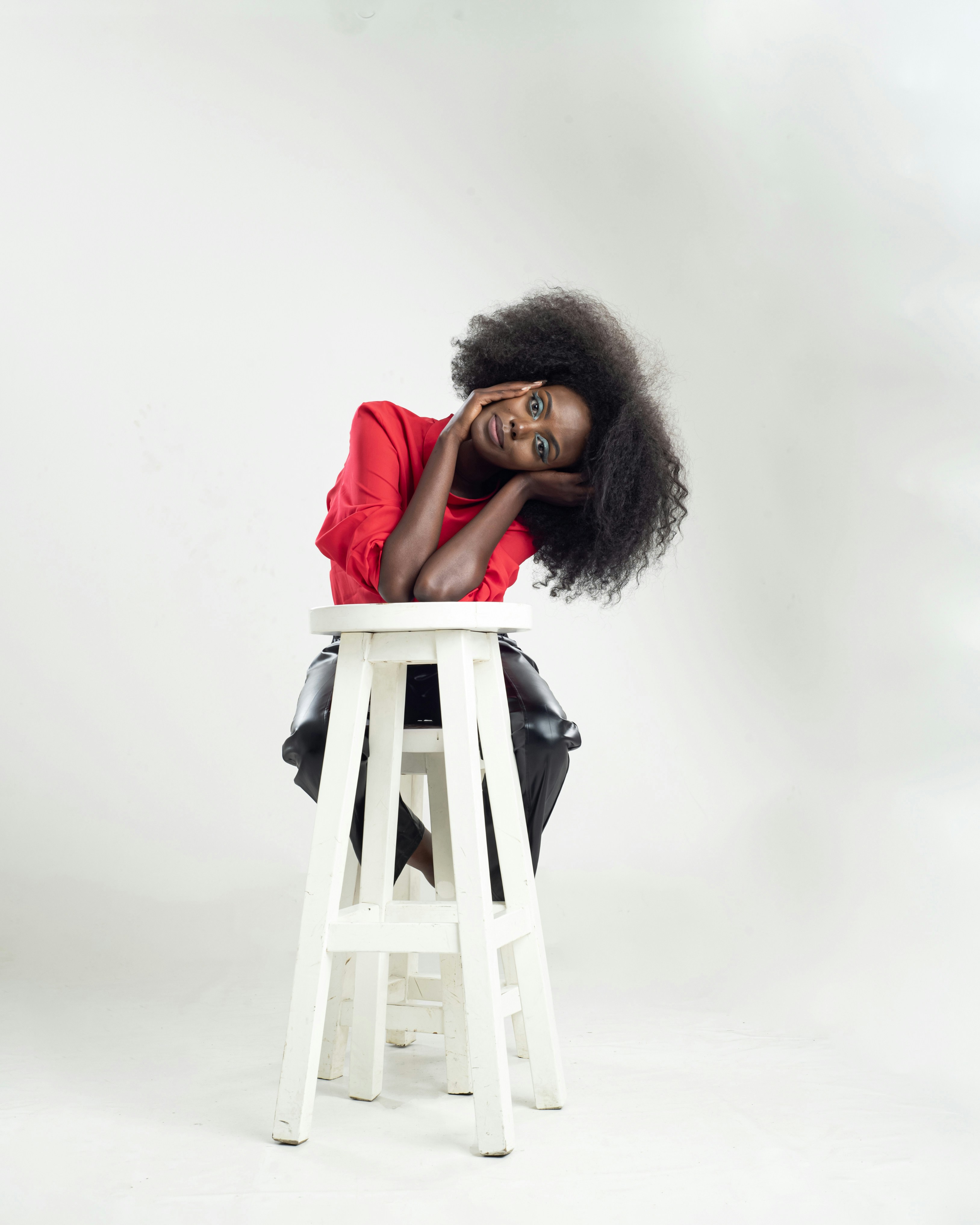 A woman sitting on top of a white stool