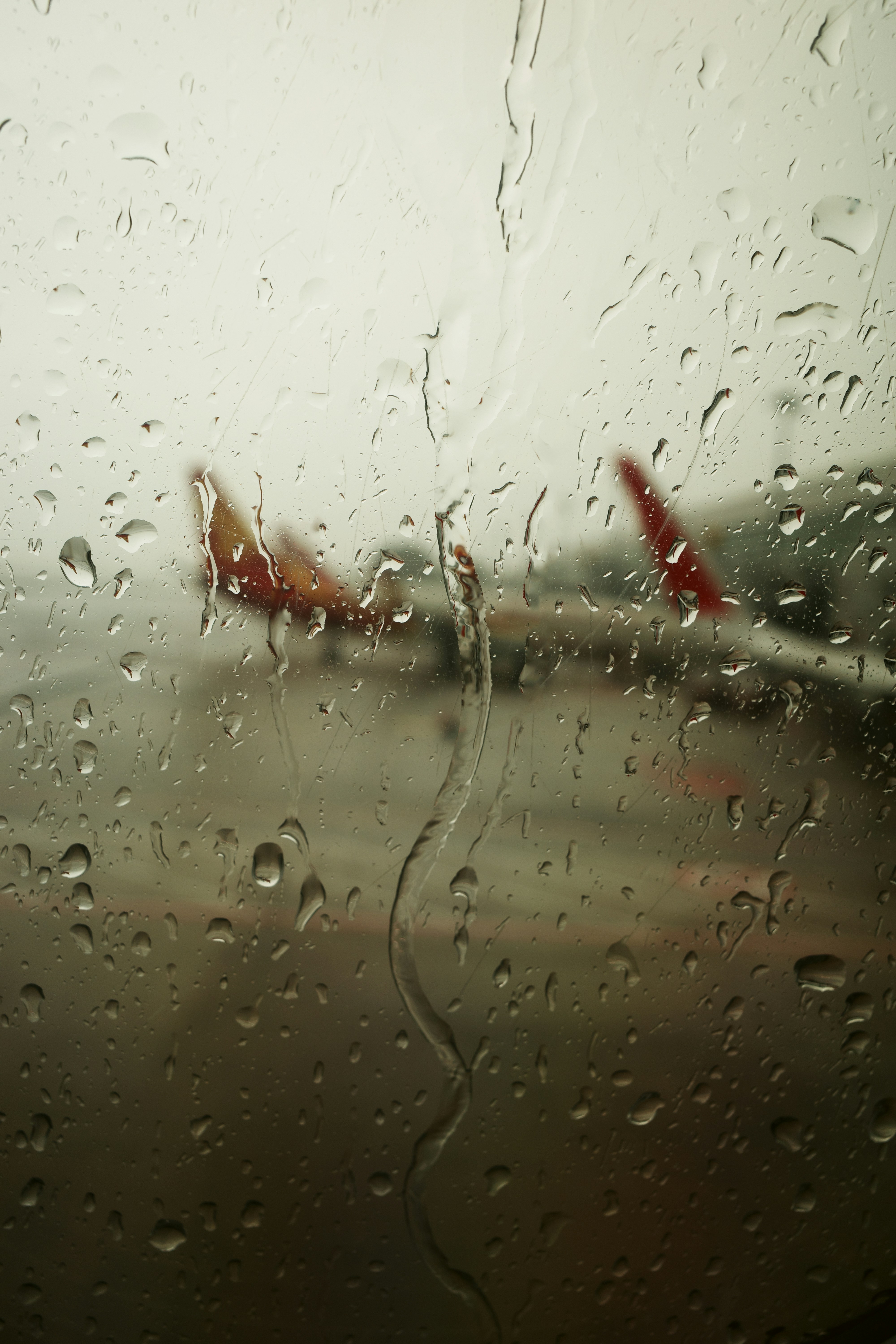 A view of an airport through a rain covered window