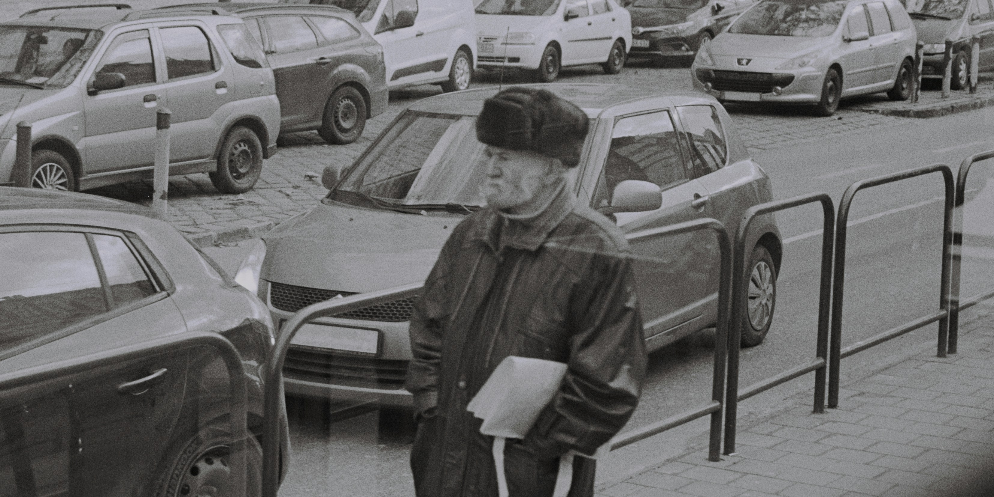 A black and white photo of a man standing on the side of a road