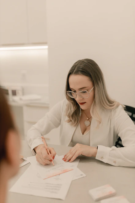 A woman sitting at a table writing on a piece of paper