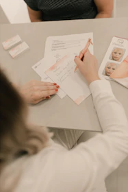 A woman sitting at a table writing on a piece of paper
