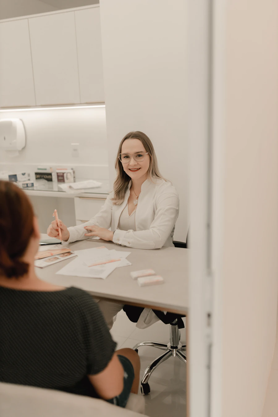 Clinician in a white coat consulting with a client in a bright aesthetic clinic