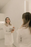 A woman standing in front of a mirror holding a clipboard