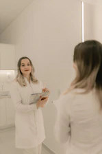 A woman standing in front of a mirror holding a clipboard