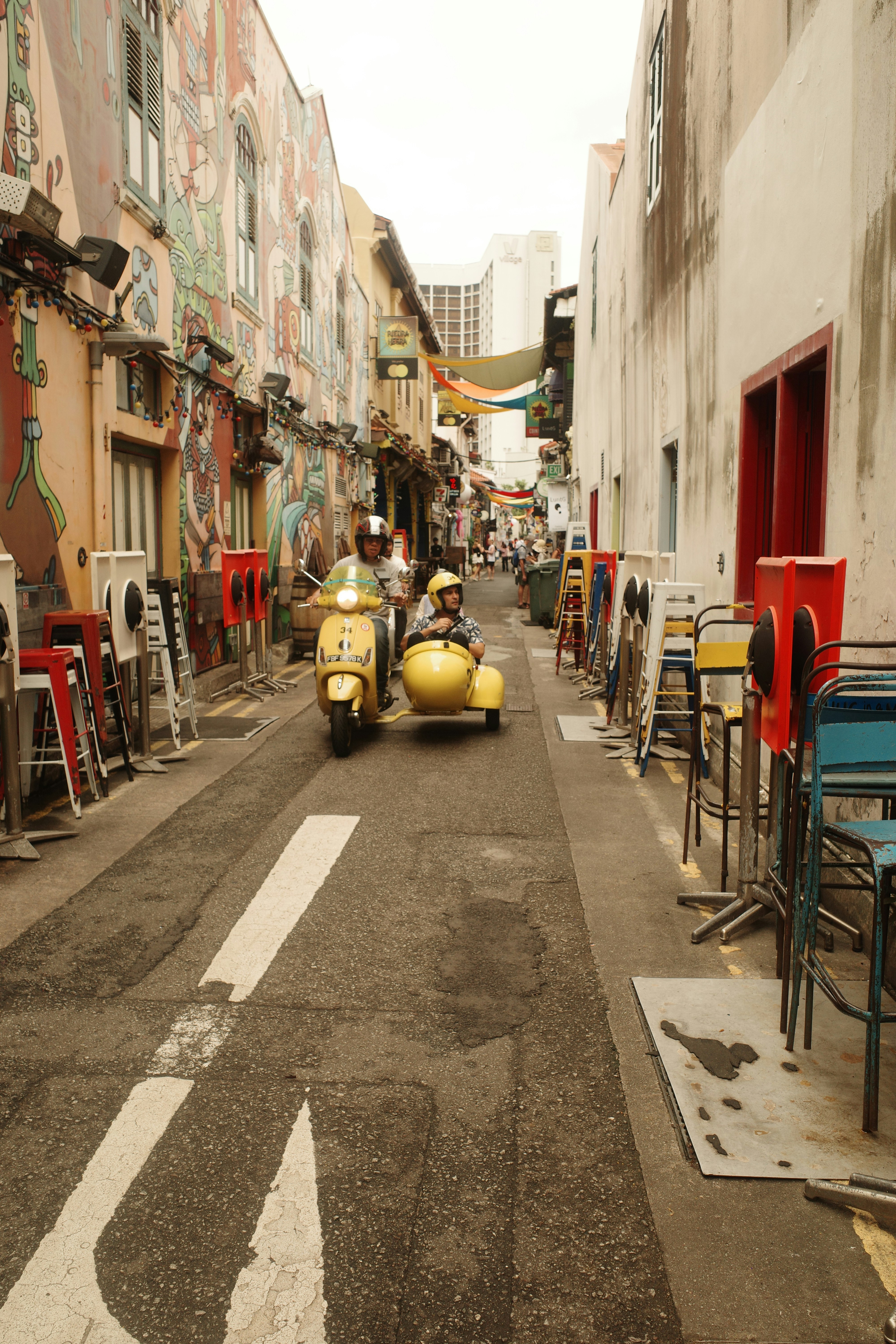 A narrow street with a yellow motorcycle parked on the side of it