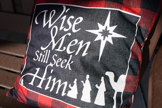 A red and black pillow sitting on top of a wooden bench