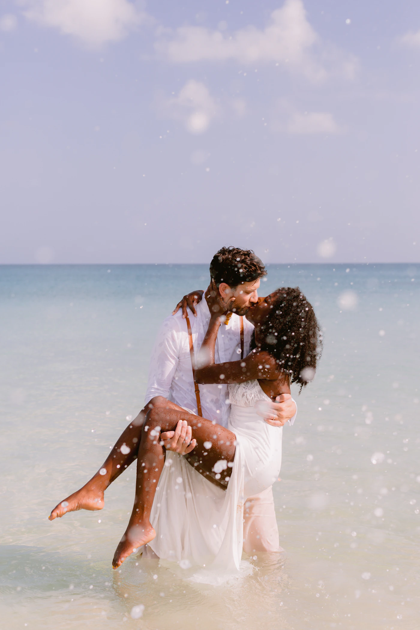 Couple in white elopement attire at El Almejal beach in Bahia Solano with the Choco jungle visible behind them and the Pacific ahead
