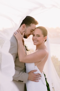 A bride and groom embracing under a veil