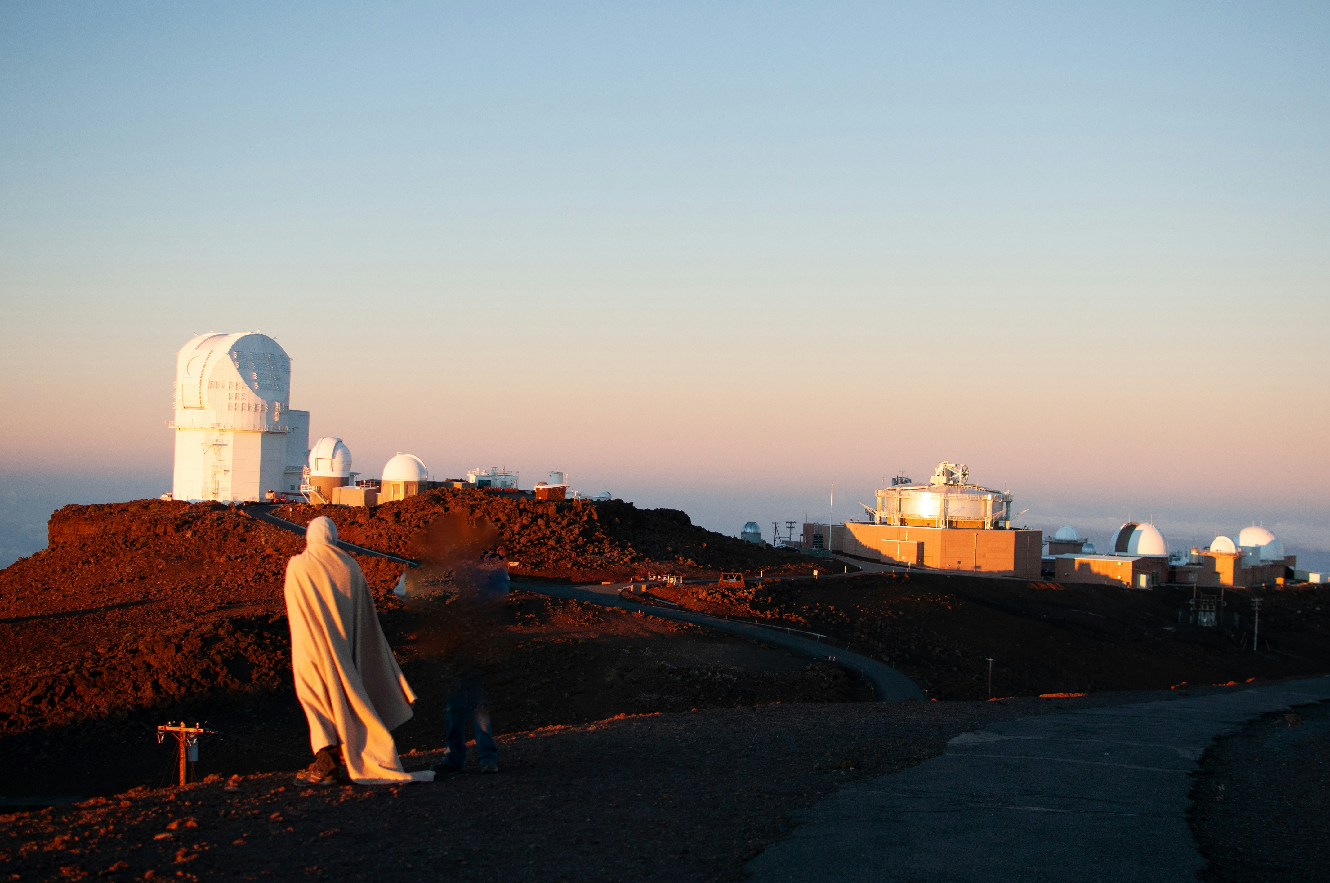 A man standing on top of a hill next to a satellite dish