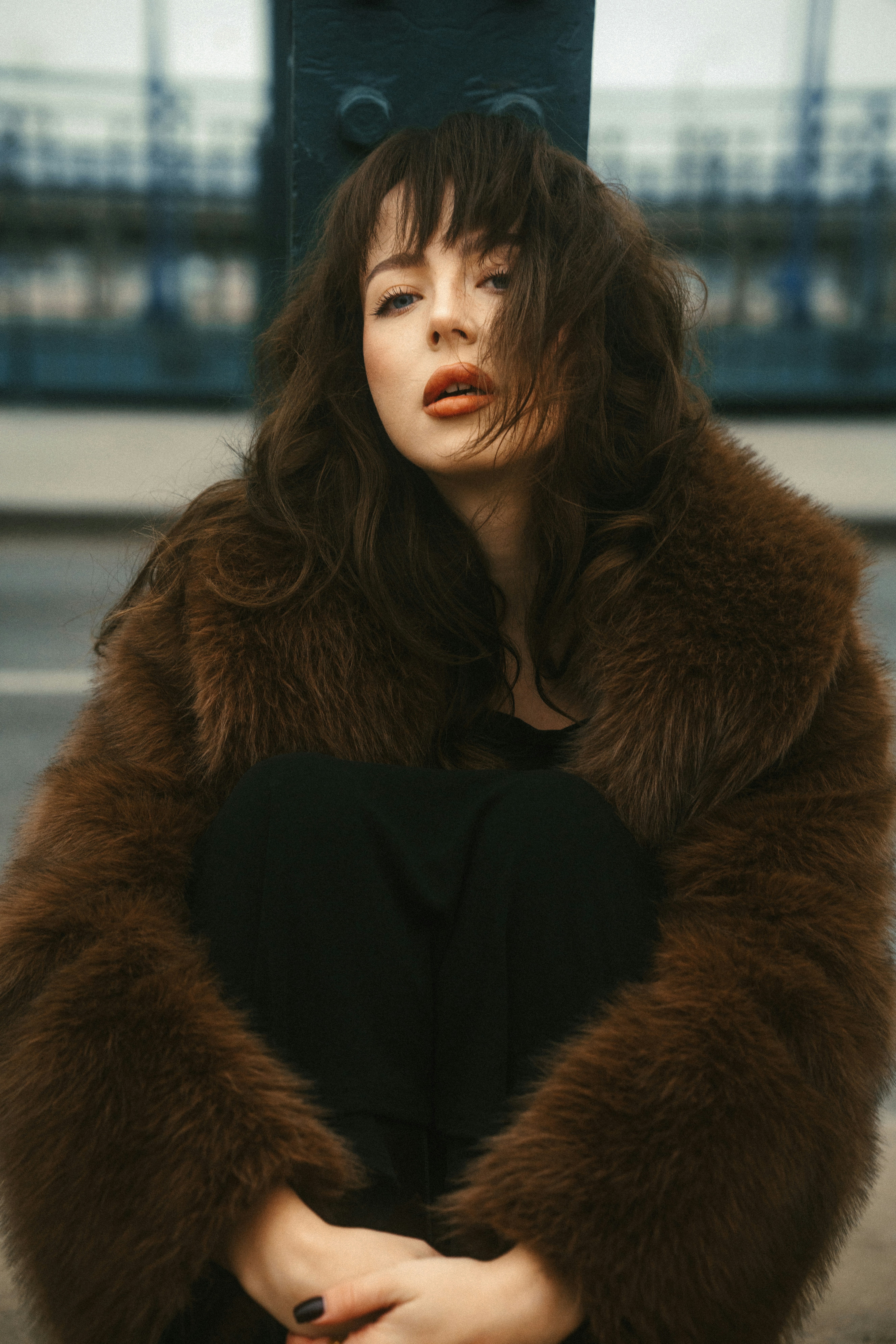 A woman in a fur coat sitting on a bench