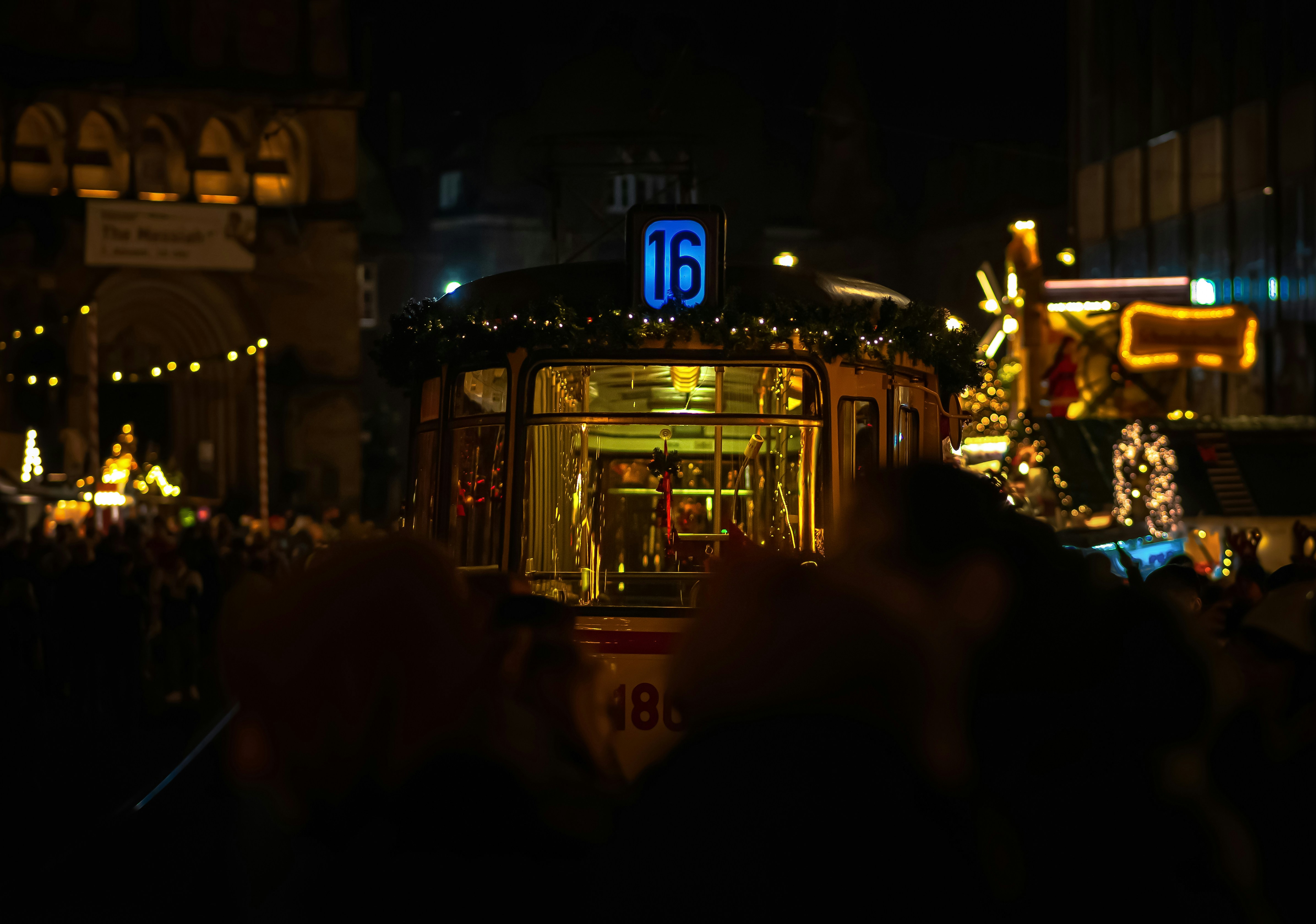A crowd of people standing around a trolley at night