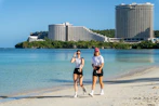 A couple of people that are standing in the sand