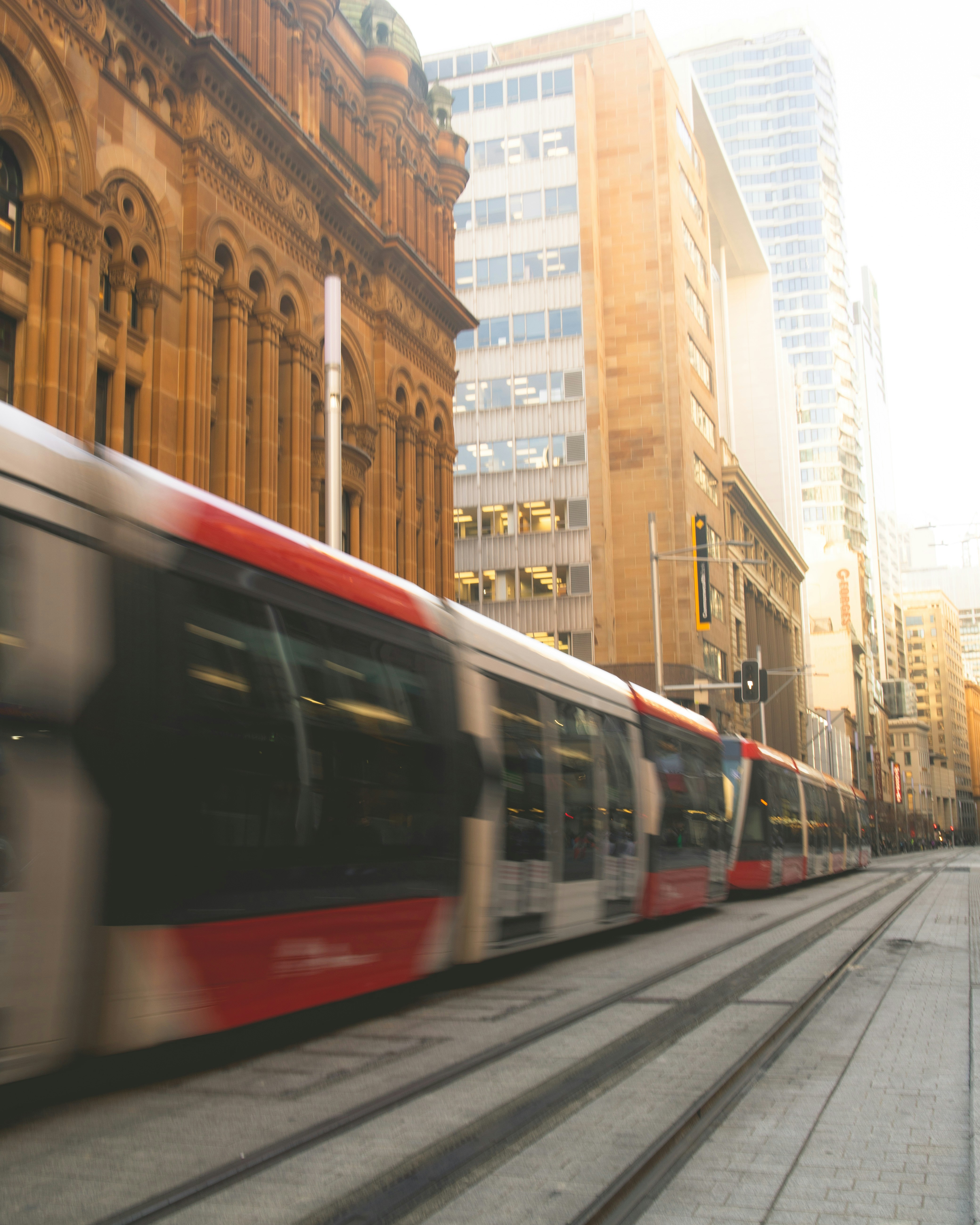 A train traveling down a street next to tall buildings