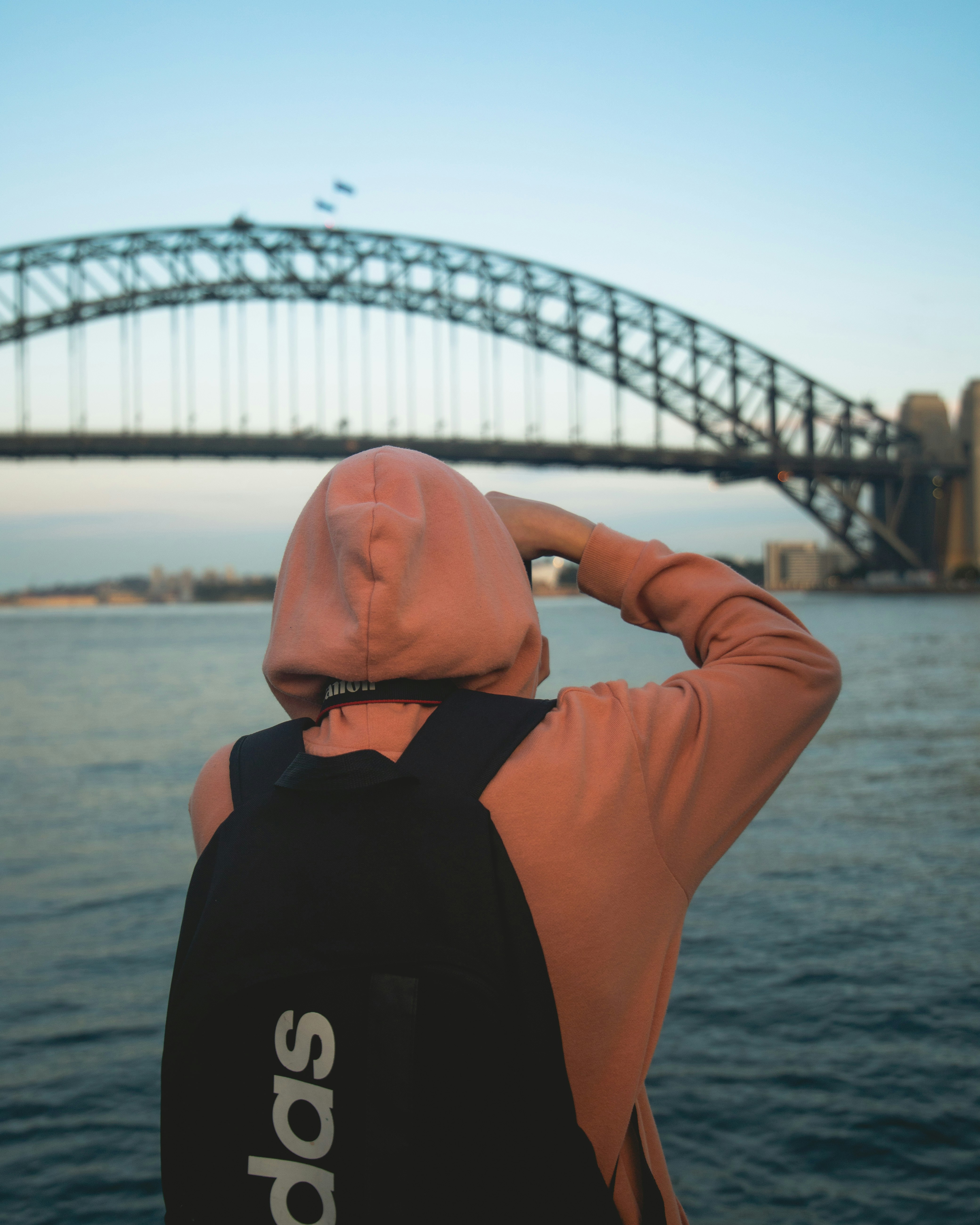 A man standing in front of a bridge looking at the water