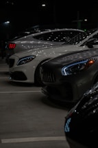 A group of cars parked in a parking lot at night