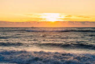 The sun is setting over the ocean waves