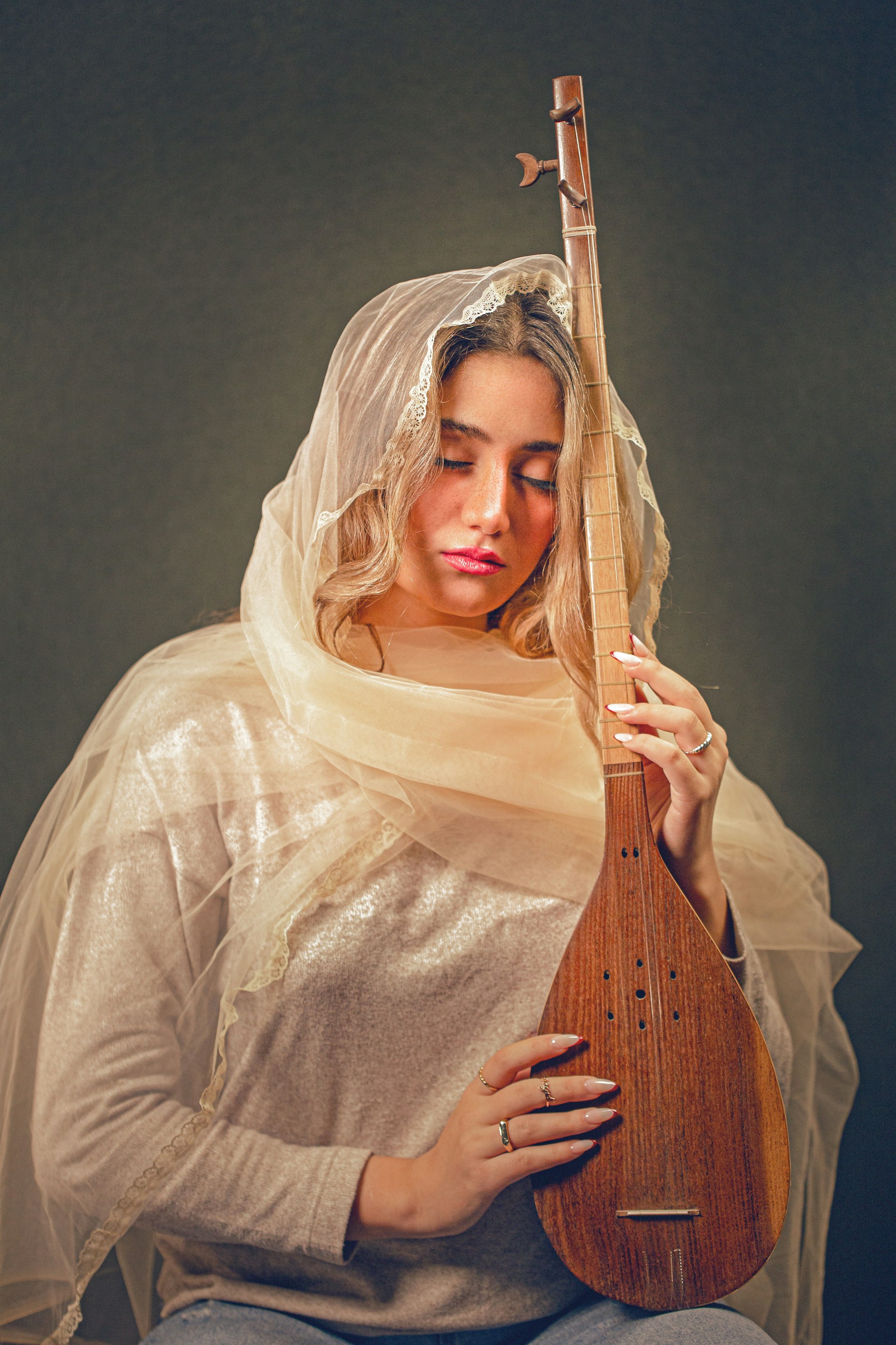 A woman in a veil holding a wooden instrument