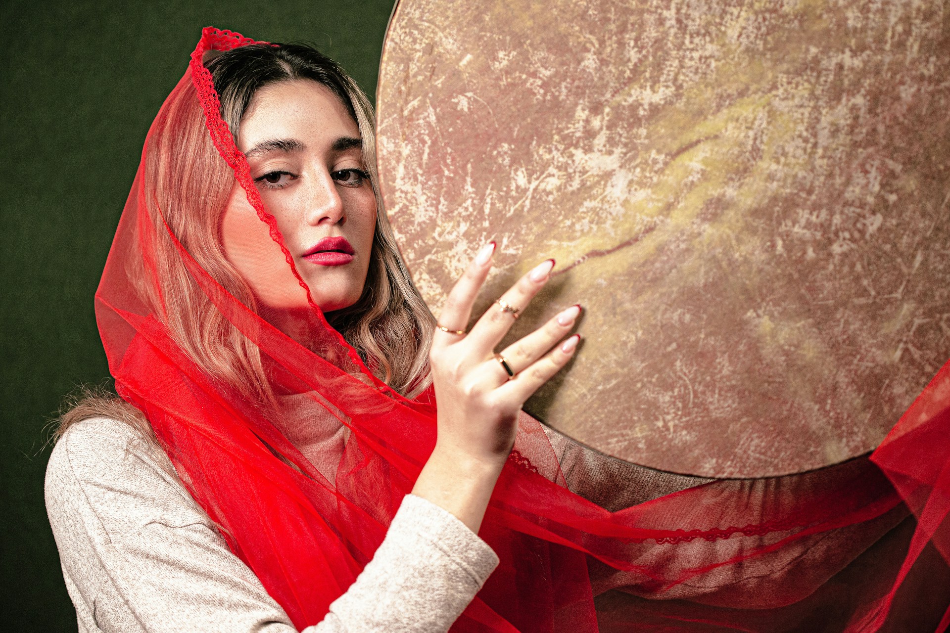 A woman in a red veil is holding a large object