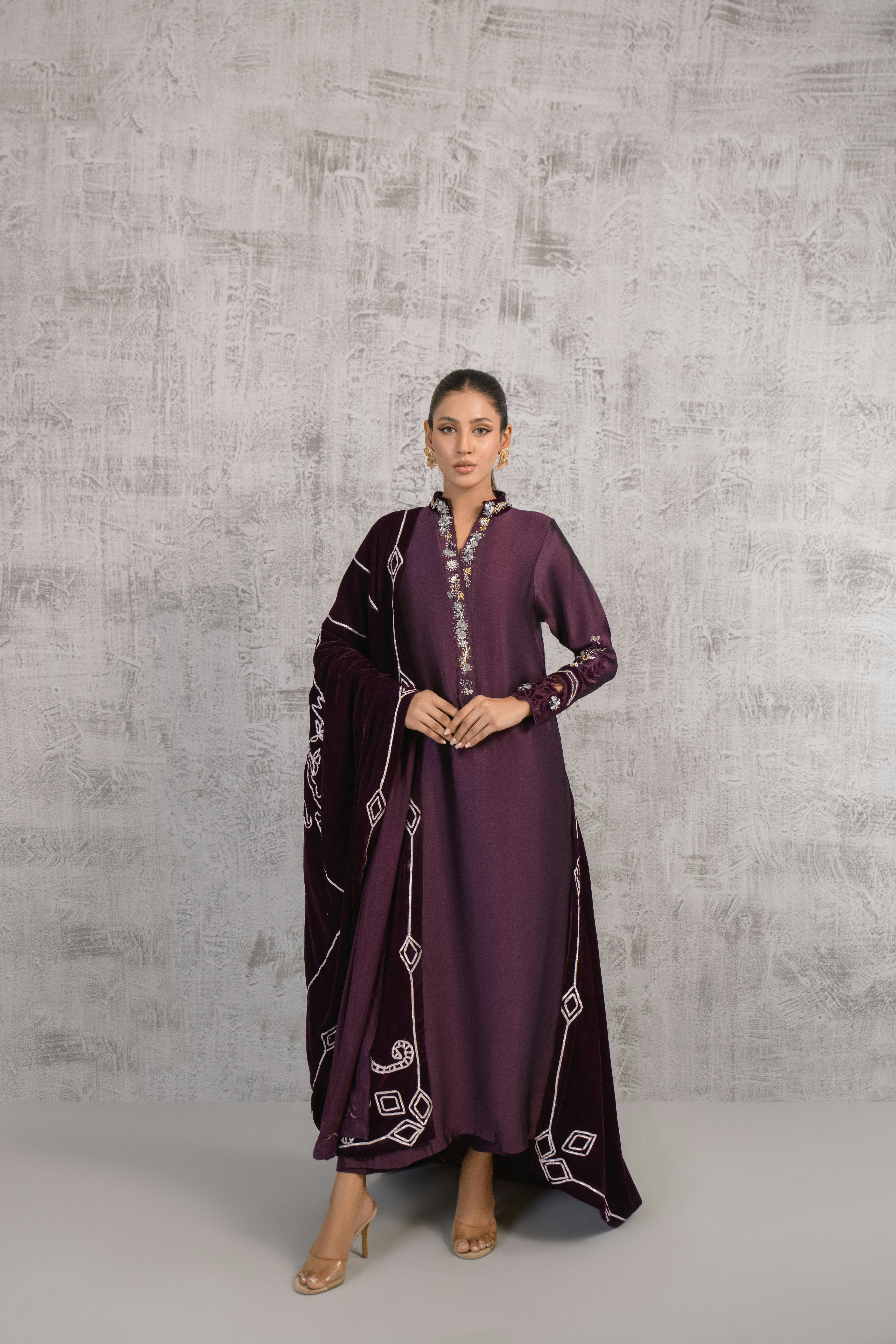 A woman in a purple dress standing in front of a wall