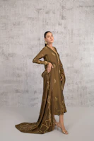 A woman in a brown dress standing in front of a wall