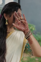 A woman in a white sari holding her hands up to her face