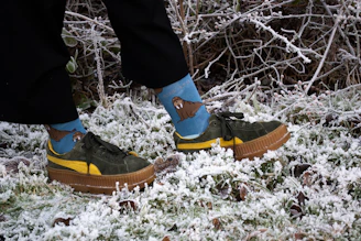 A person wearing green and yellow shoes standing in the snow