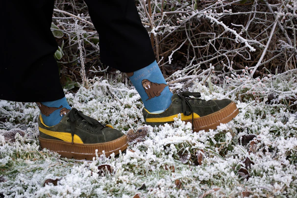 A person wearing green and yellow shoes standing in the snow