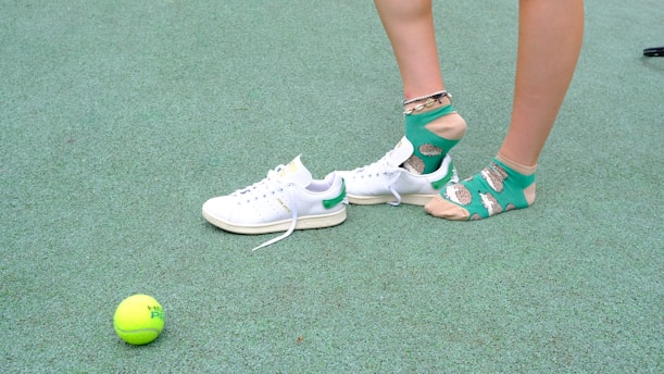 A person standing next to a tennis ball on a court