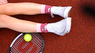 A woman laying on the ground with a tennis racket and ball