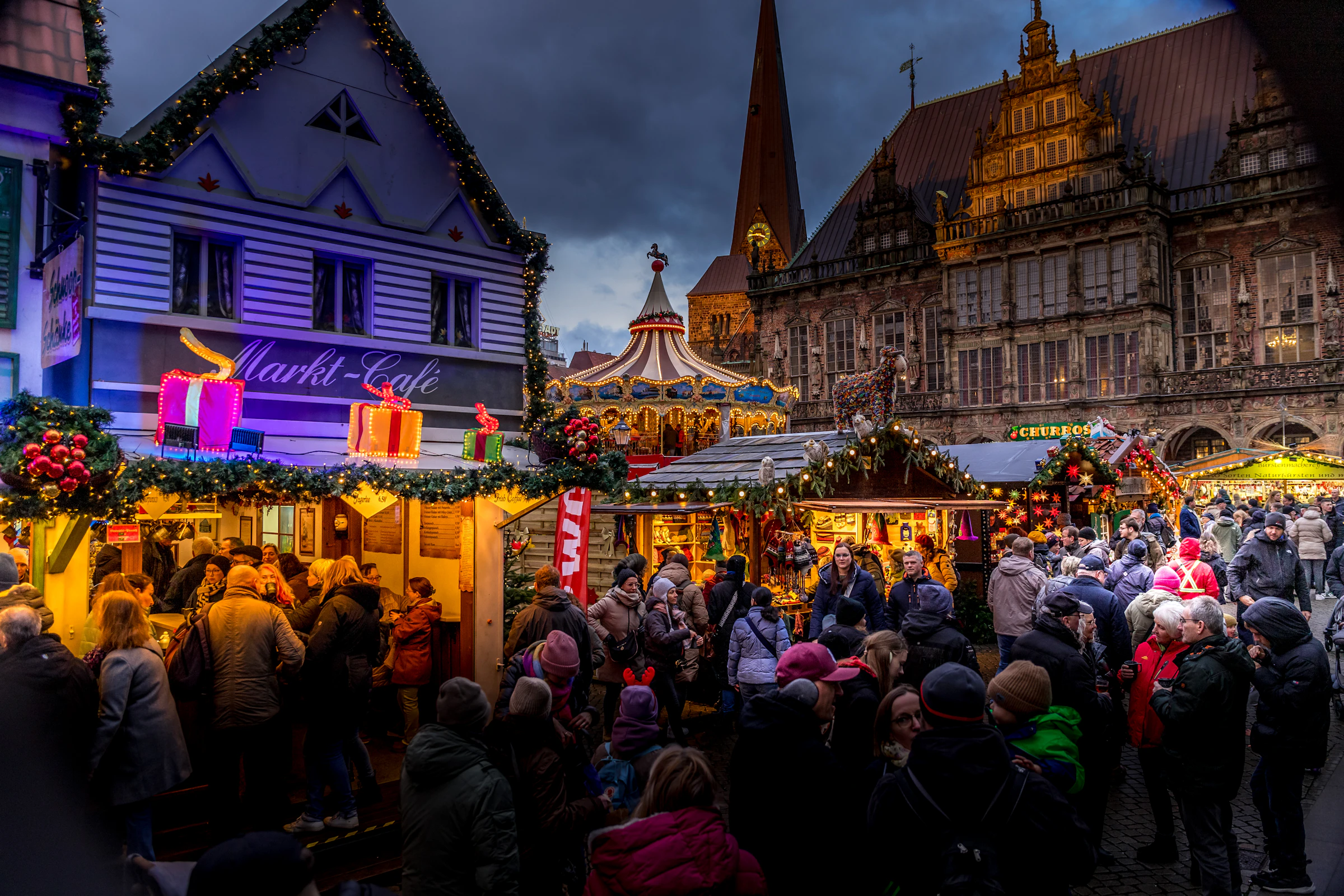 Drukte op een kerstmarkt voor een historisch stadhuis